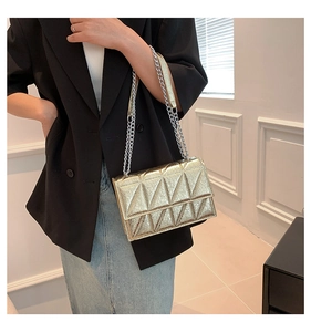 Detail of a gold quilted chain bag with triangular stitching and metallic finish
