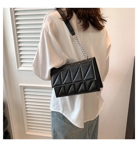 Detail of black quilted leather shoulder bag with triangle pattern and chain strap