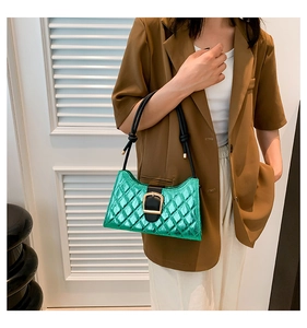 Detail of green metallic quilted baguette bag with gold buckle and black shoulder straps