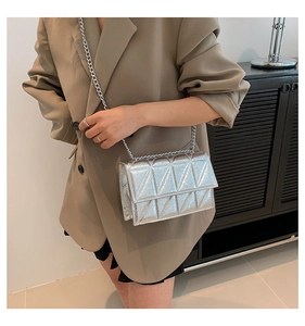 Detail of silver metallic crossbody bag with geometric quilting and fine chain strap