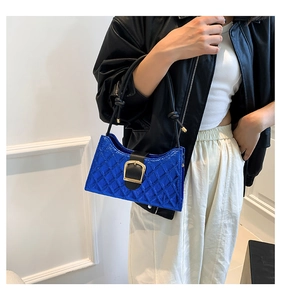 Detail of bright blue quilted leather shoulder bag with gold buckle and knotted strap