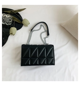Vue de dessus d'un sac bandoulière matelassé noir avec chaîne argentée sur blanc