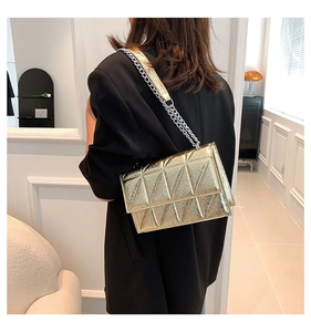 Close-up of a metallic gold geometric quilted crossbody bag with a chain strap on a model