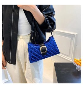 Detail of royal blue quilted handbag with bold black strap and gold metal buckle