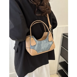Minimalist blue denim underarm bag with tan leather trim and adjustable strap