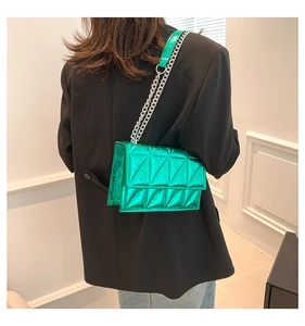 Close-up of metallic green quilted crossbody bag with silver chain strap on model
