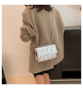 Close-up of silver quilted crossbody bag with triangular stitching and chain strap