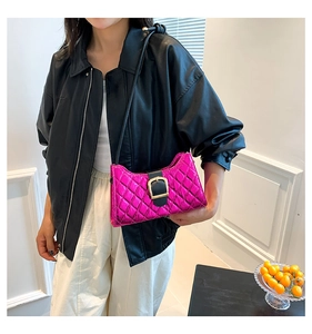 Close-up of fuchsia baguette bag featuring diamond quilting and a gold buckle