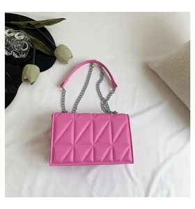 Vue de dessus du sac bandoulière matelassé rose vif avec chaîne argentée sur tissu blanc
