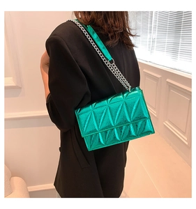 Close-up of metallic green quilted crossbody bag with silver chain worn by a model