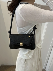 Minimalist black crocodile pattern underarm bag with gold buckle shown on a model