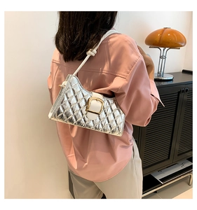 Detail of silver quilted baguette bag with white strap and golden buckle on model