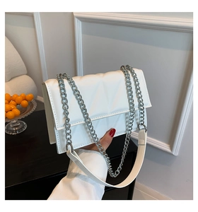 Détail du sac bandoulière blanc matelassé avec chaîne argentée et coutures géométriques