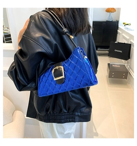 Detail of blue quilted baguette bag with gold buckle on a model's shoulder