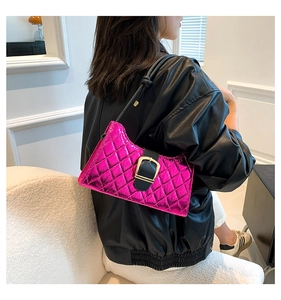 Detail of pink quilted baguette bag with gold buckle and black shoulder strap on model