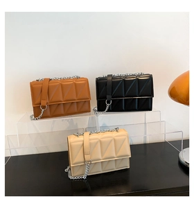 Trois sacs à chaîne matelassés en caramel, noir et blanc crème sur un présentoir