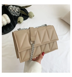 Détail du sac à bandoulière beige avec chaîne argentée et gaufrage géométrique