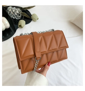 Gros plan du petit sac matelassé marron avec coutures triangles et chaîne argentée