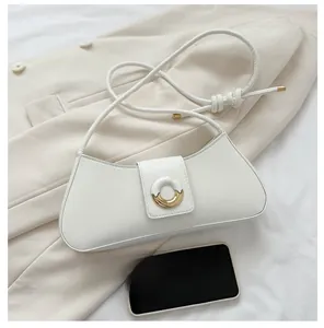Detail of creamy white crescent shoulder bag with bimetal buckle on beige fabric