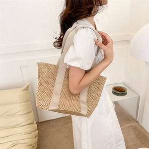 Close-up of woven straw tote bag featuring reinforced base and wide canvas straps