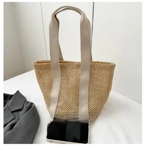 Top-down view of woven beach tote bag next to a smartphone for size reference