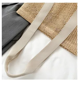 Detail view of woven straw beach bag featuring durable cream canvas handles and texture