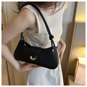 Detail of black faux leather underarm bag with gold circular buckle and knotted strap