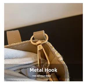 Detail of golden metal hook on woven straw bag with khaki leather and canvas lining