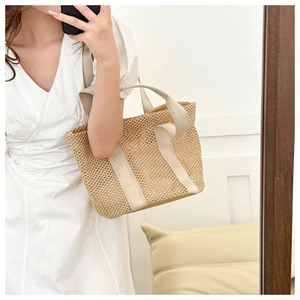 Detail of hollow woven beach bag with beige canvas handles and pastoral texture