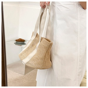 Detail of woven straw tote bag with cream canvas straps for summer beach vacations