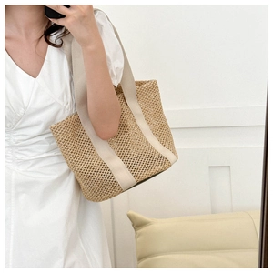 Detailed texture of hollow woven straw beach bag with durable cream textile straps