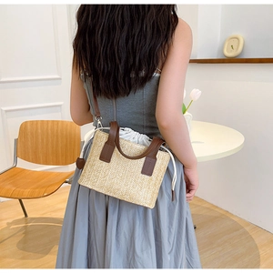 Detail of hand-woven straw crossbody bag with leather straps and a drawstring inner lining