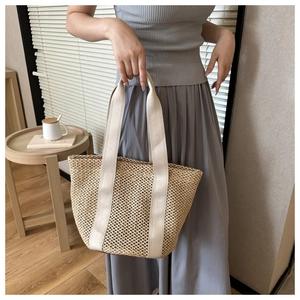 Detail of hand-woven hollow straw tote bag with white canvas handles for beach vacations