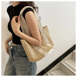 Detail of hollow woven beach tote featuring cream textile straps and a color-block bottom