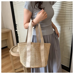 Detail of a beige woven straw beach bag with parallel fabric handles for vacation