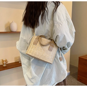 Detail of straw woven crossbody bag featuring khaki leather strap on model for summer