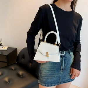 Chic white trapezoid crossbody handbag with gold metal clasp worn by a female model