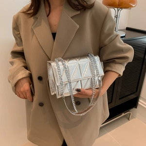 Silver geometric quilted crossbody bag with metal chain strap worn by a model