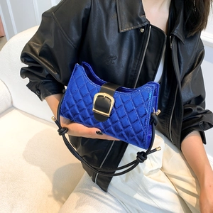 Royal blue quilted baguette bag with metallic finish and gold buckle shown on a model