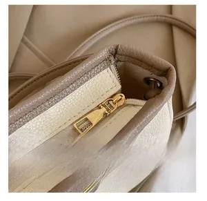 Détail de la fermeture éclair dorée et du cuir crème texturé de ce sac à main chic