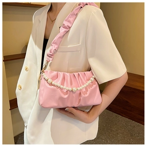 Borsa rosa a pieghe con catena di perle abbinata a un outfit con blazer bianco