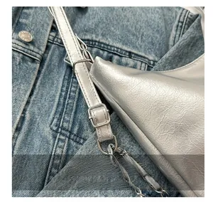 Detail of adjustable silver square metal buckle and faux leather chain strap on a bag