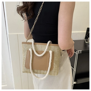 Detail der Strohtasche mit dicken Baumwollseilgriffen und goldener Ketten-Schultergurt