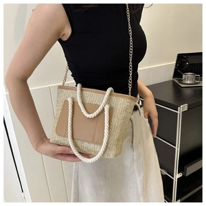 Detail der Strohtasche mit weißem Seilgriff und goldener Kettenriemen für Damen