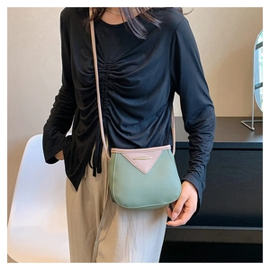 Sac seau bandoulière vert et rose en similicuir avec boucle dorée porté par un mannequin