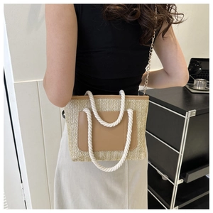 Stroh-Eimertasche mit brauner Ledertasche und Seilgriff an einem Modell gezeigt
