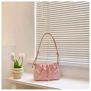 Detail of light pink ruched cloud bag featuring pearl chain and gold flower accents
