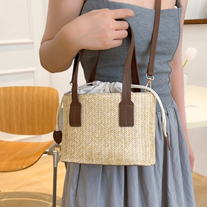 Minimalist straw woven tote bag with brown leather handles and adjustable shoulder strap