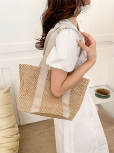 Minimalist straw woven tote bag with white handles for beach vacation and casual use
