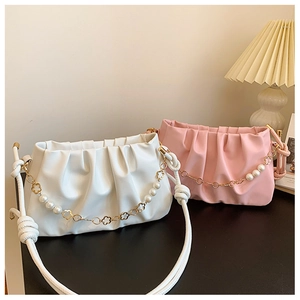 Detail of ruched cloud bags with pearl flower chains and knot straps in a soft indoor setting